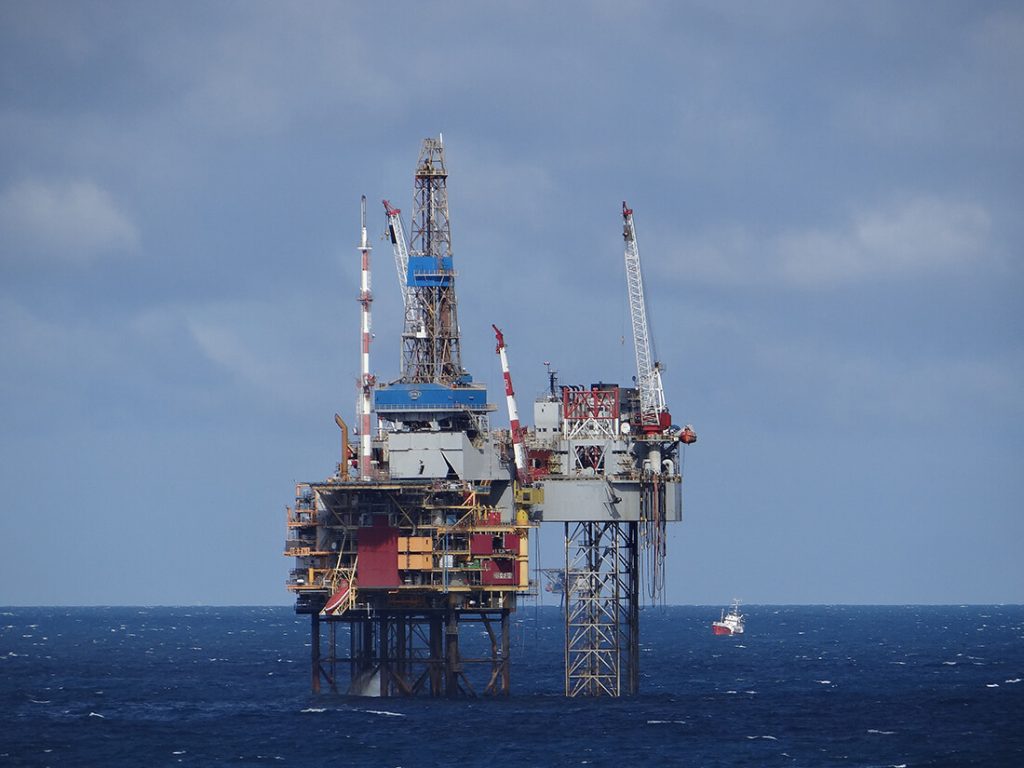 Offshore oil rig in the ocean under a cloudy sky.