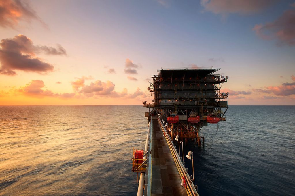 Offshore oil rig platform at sea during sunset.