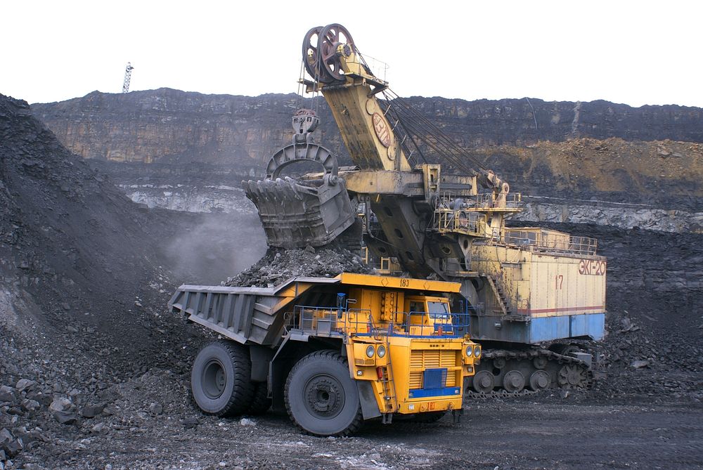 Large excavator loading coal into a dump truck at a mining site.