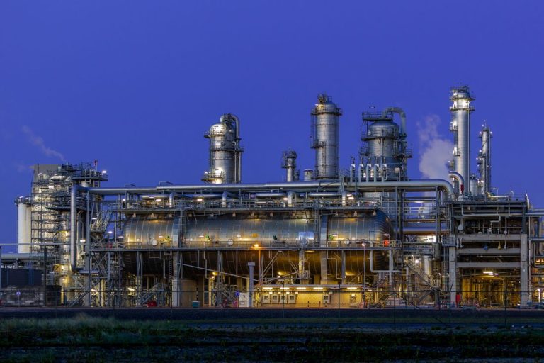 Industrial plant illuminated at dusk with metal structures.
