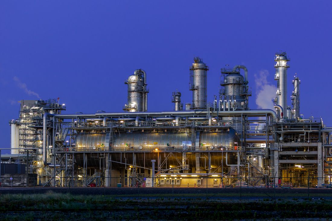 Industrial plant illuminated at dusk with metal structures.
