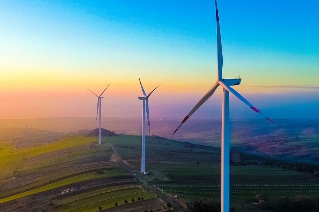 Wind turbines on rolling hills at sunset.