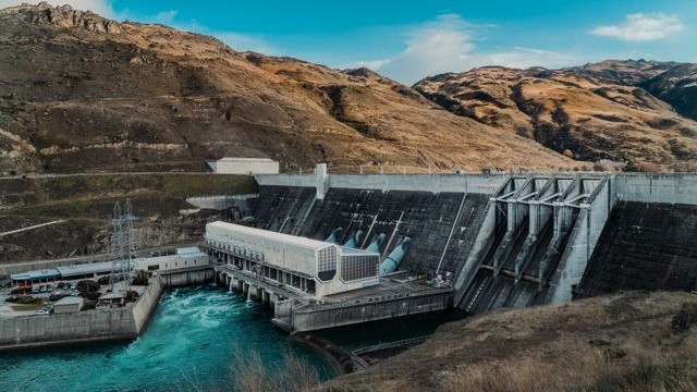 A large dam with flowing water in a mountainous area.