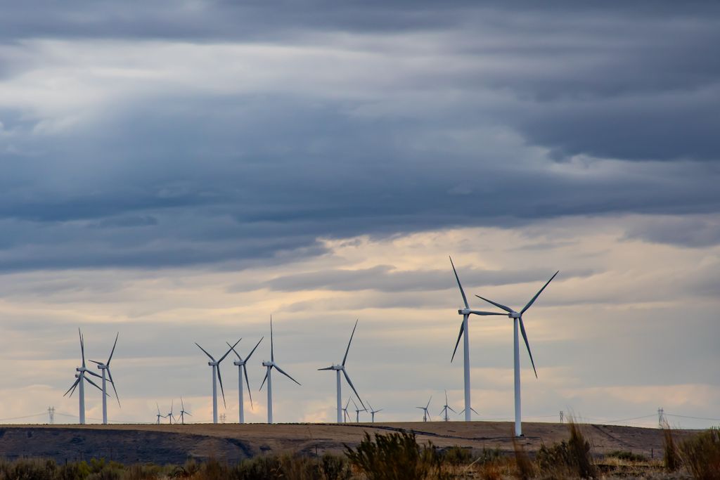 Wind turbines on a hilly landscape under a cloudy sky.