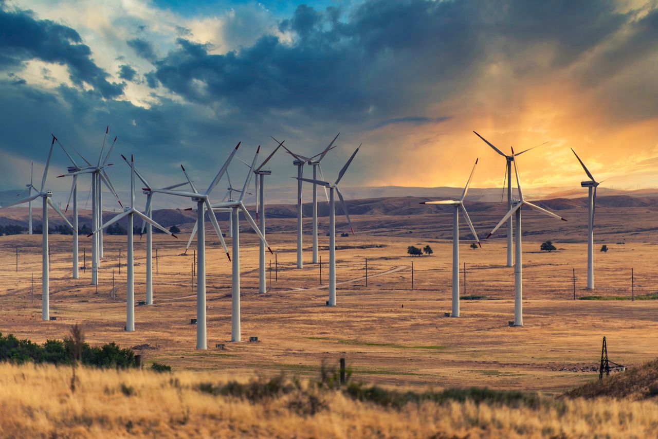 Wind turbines on a vast open field at sunset.